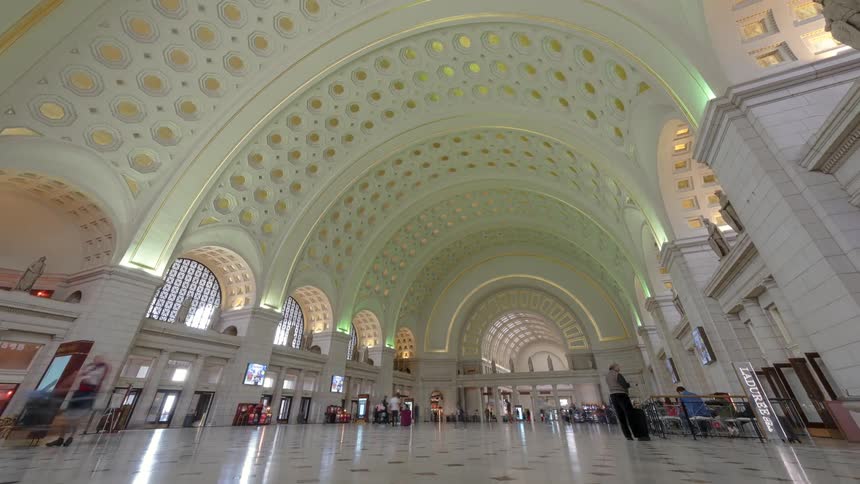 A large hall with black and white floors with people walking and standing around