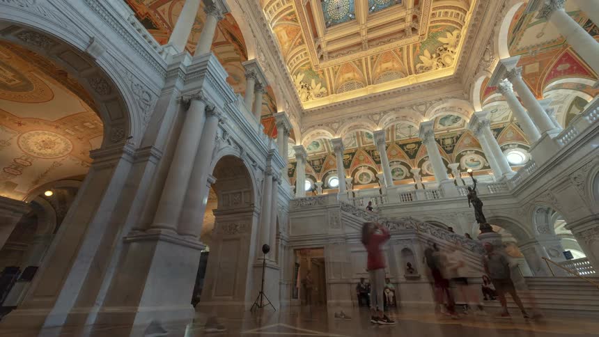 Tourists walking around and photographing the inside of a building with painted ceilings