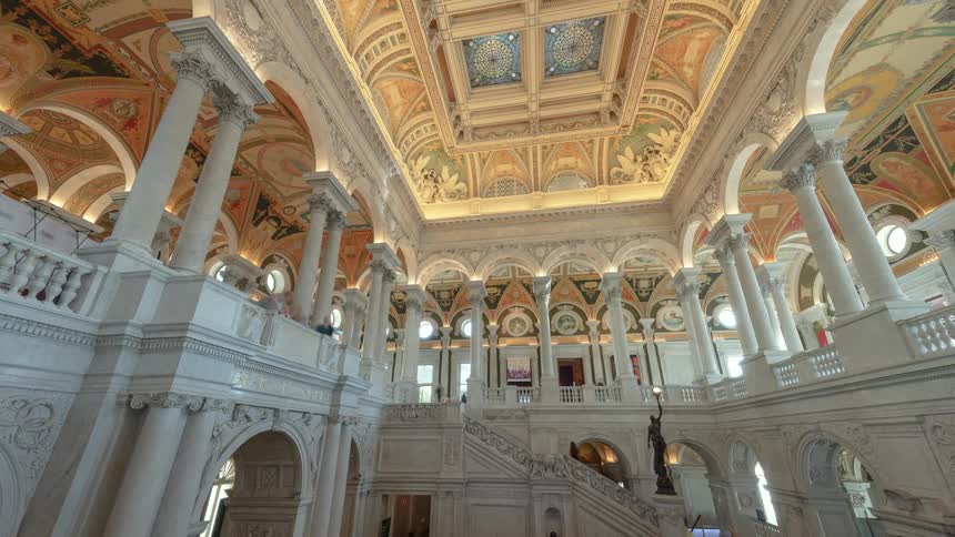 People walk up and down stairs in an ornate building