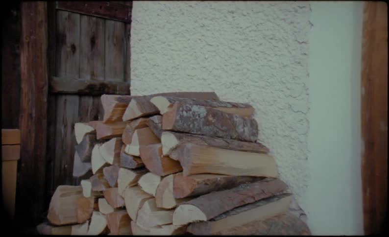 Firewood stacked near window as person turns on lights inside