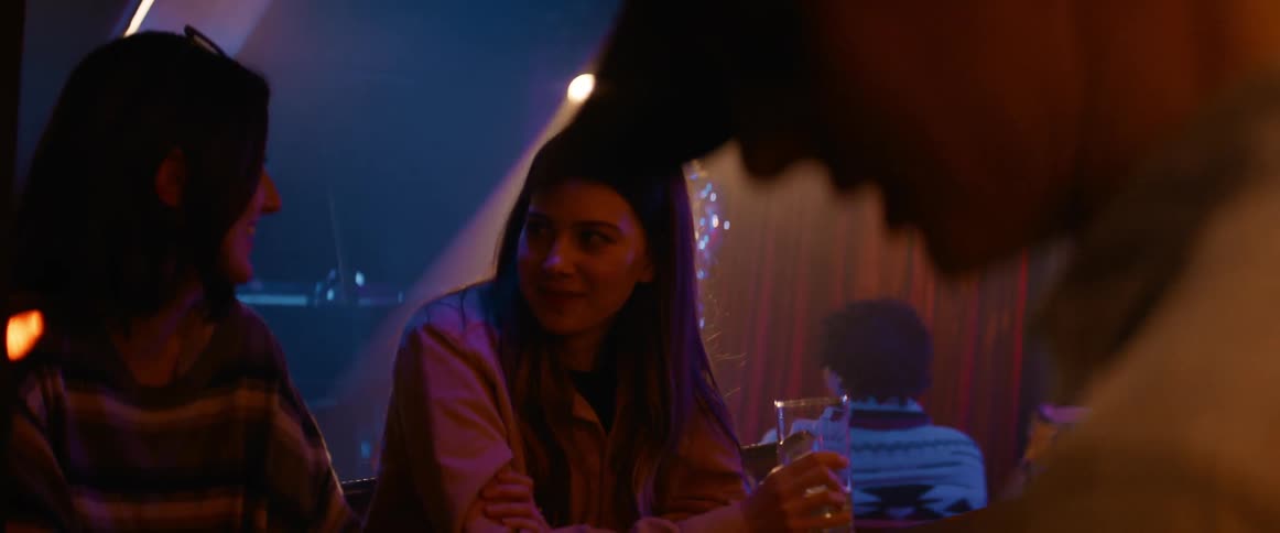 Two women chat and drink while sitting at the bar in a lounge