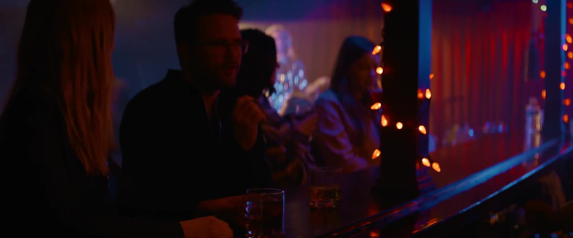 People sit at bar in nightclub while performer sings on stage