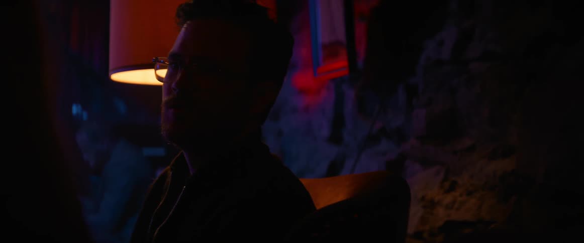 Man and woman talk in dark nightclub near table lamp