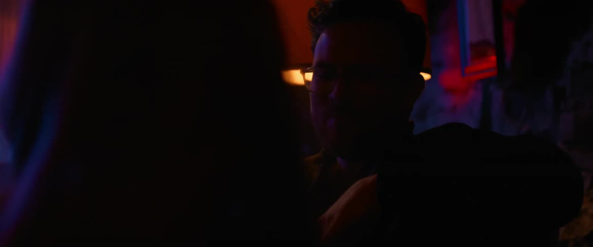 Man and woman sit and laugh together in dark nightclub