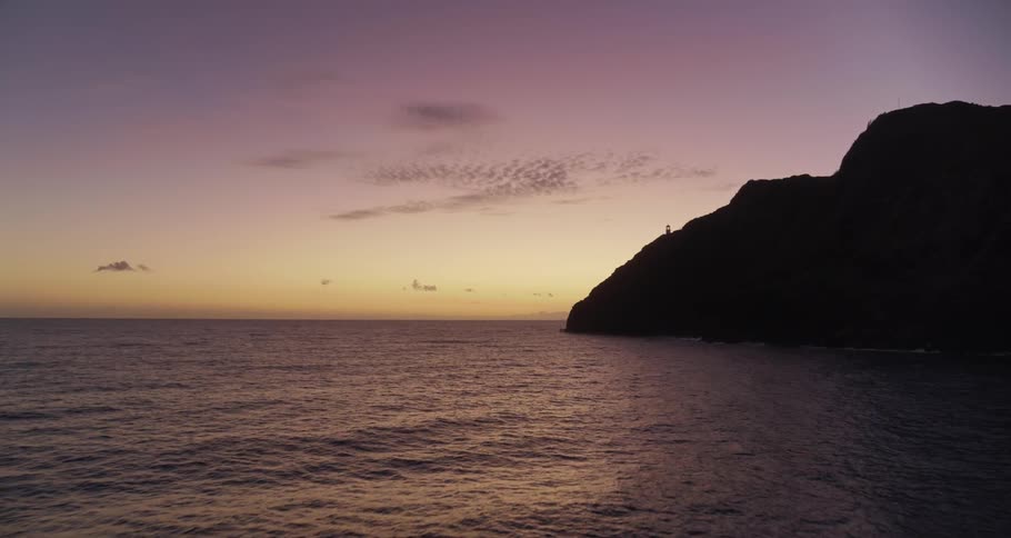 Waves roll in over the ocean under a purple sky