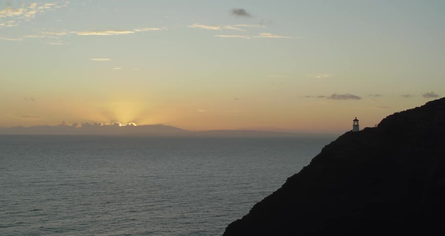 A hill next to the ocean at sunset