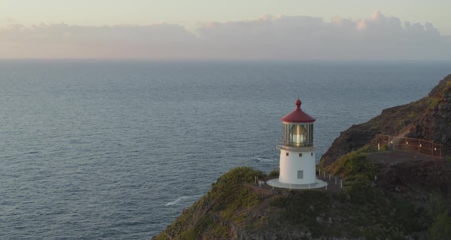 A lighthouse on top of a hill overlooking the water
