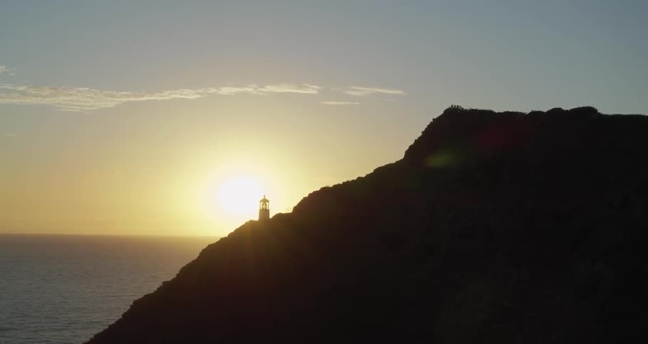 A lighthouse sits on a coastal mountain
