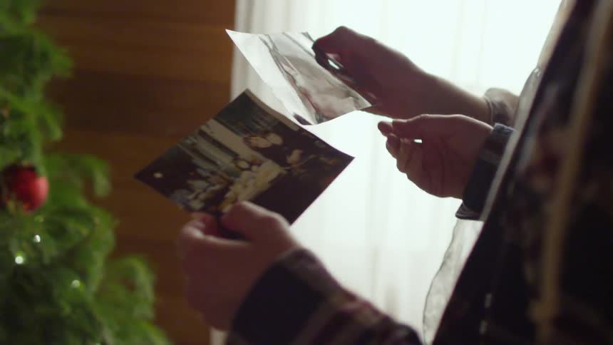 Two women looking at pictures in front of a christmas tree