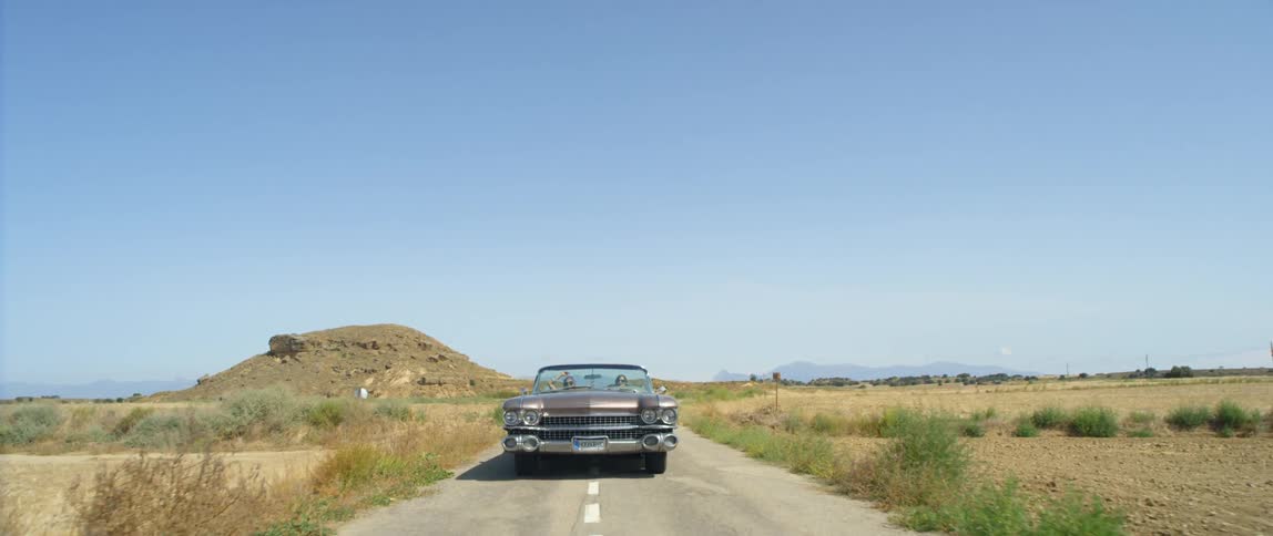 A car is driving down a road in a rural area