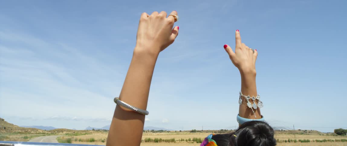 A woman is waving her hands in the air outdoors