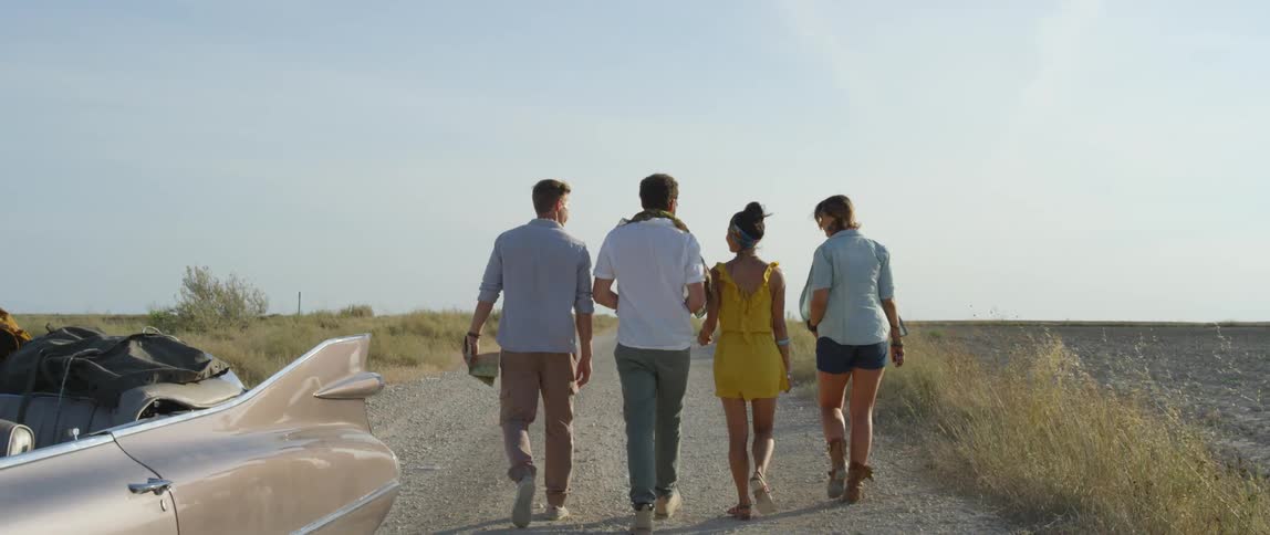 A group of friends walk on a rural dirt road on a summer day