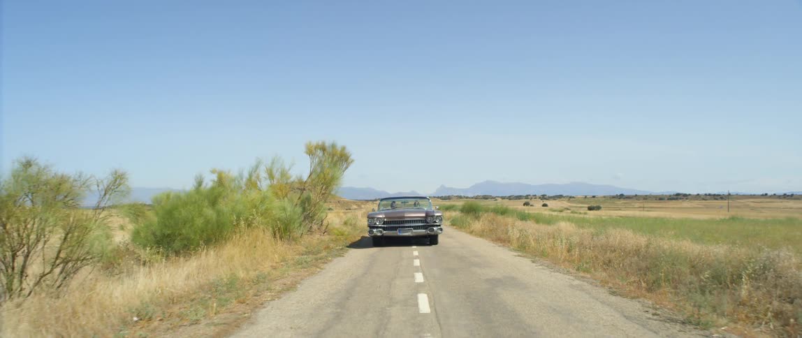 A car is driving on a road in a rural area