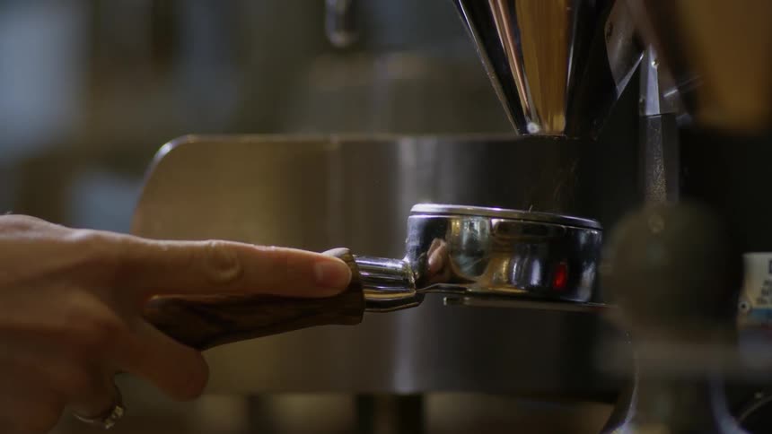 Person dispenses ground coffee into measuring cup