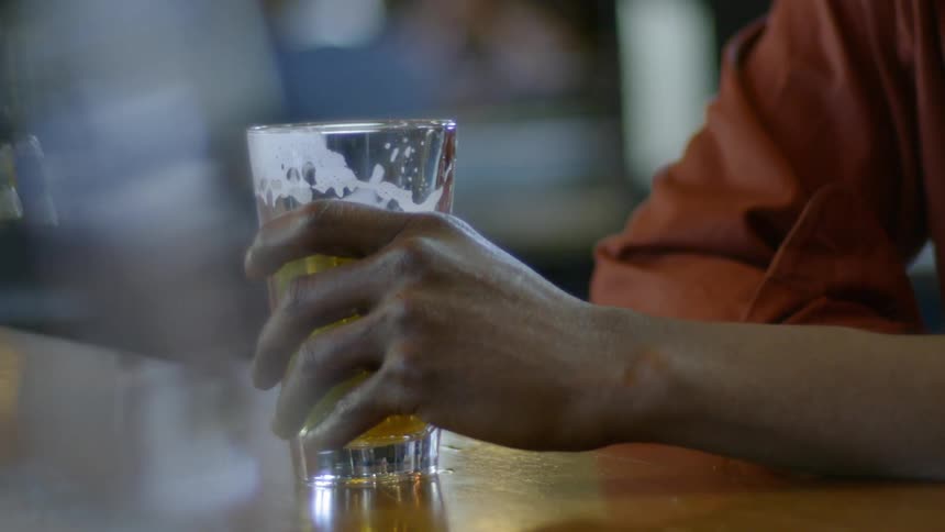 Person sits at bar holding onto beer glass