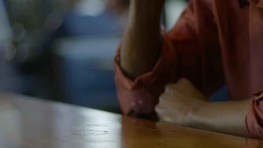 A man is drinking a glass of beer at a bar