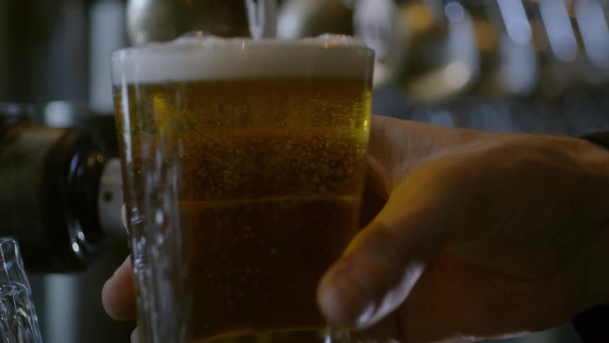 A man holds a glass of beer
