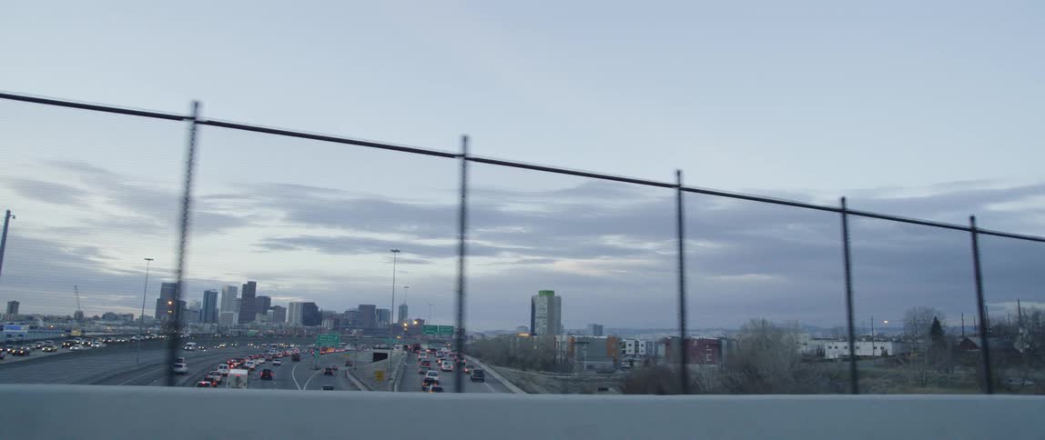 Cars are stopped in traffic going in and out of a city at dusk