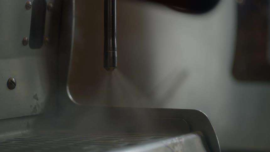 A person turns on the steamer wand on an espresso machine