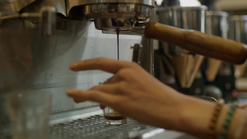 A woman uses a machine to put espresso in a cup