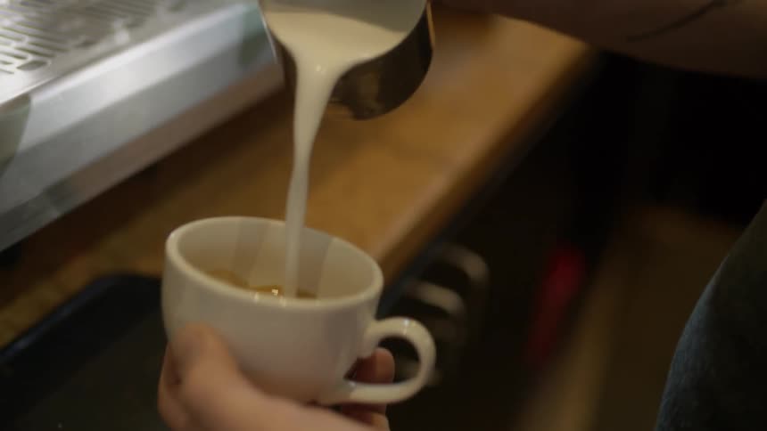 Cream is poured in a cup of coffee