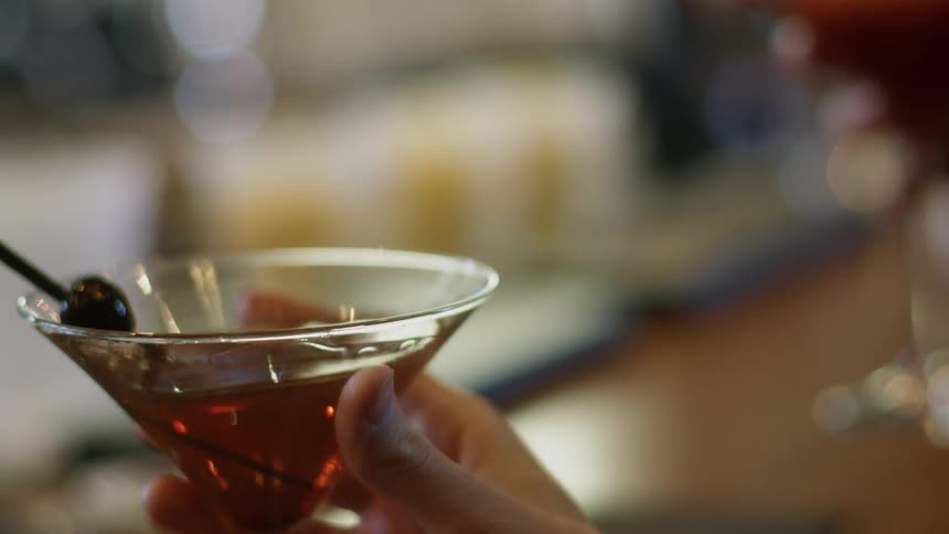 A person picks up a martini and swirls it