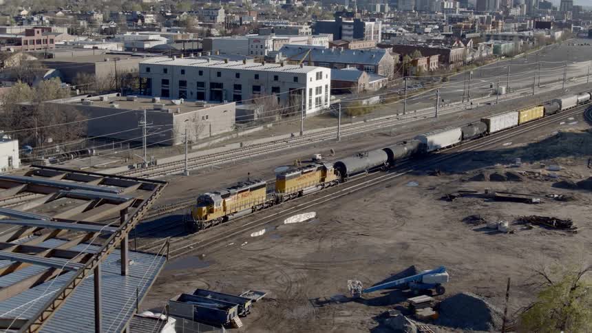 A train on a track in a train yard in the industrial area of a city on a sunny day