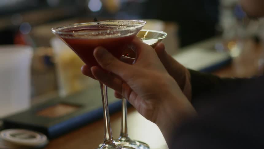 A pair of people tapping their martini glasses together