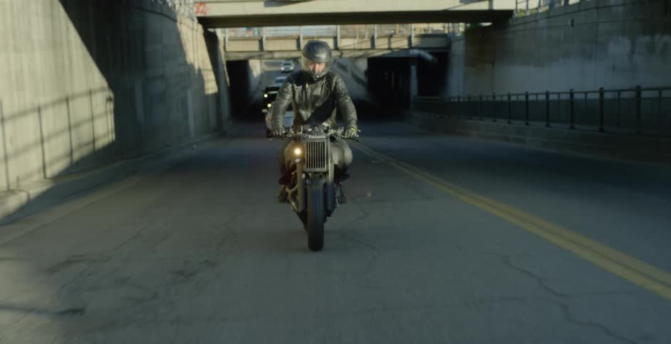 A man rides a motorcycle down a busy street