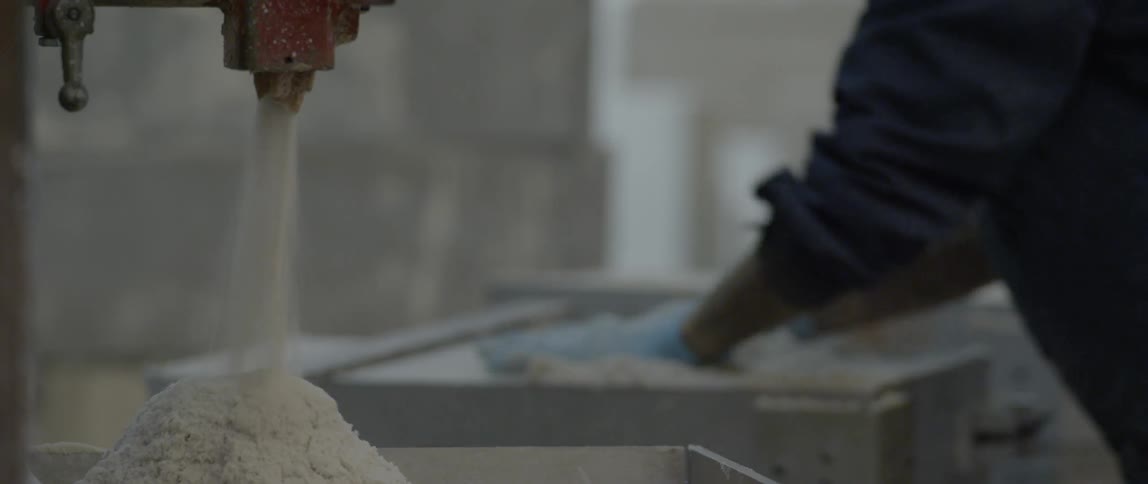 A worker smoothes out a bin full of powder