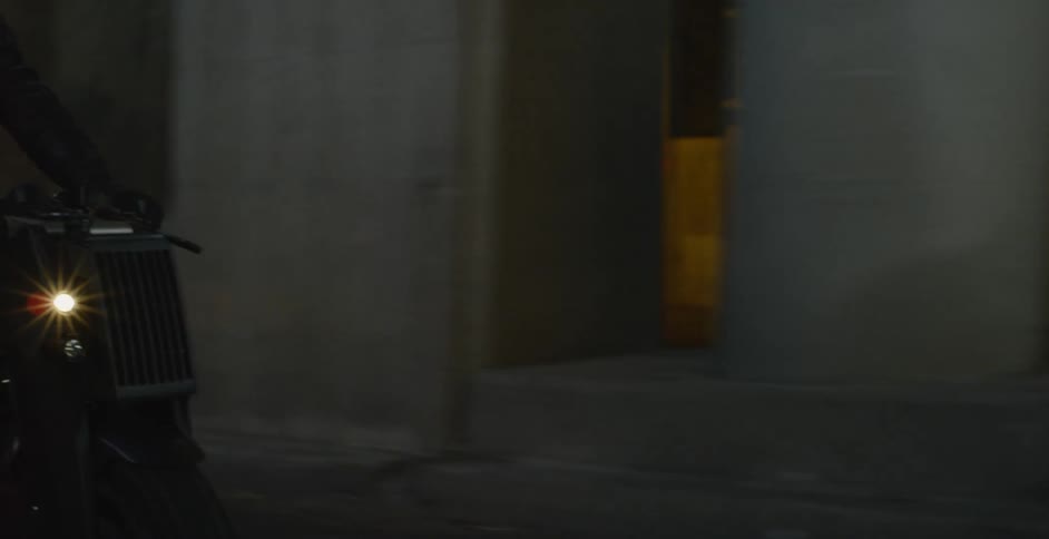 A person riding a motorcycle under a bridge