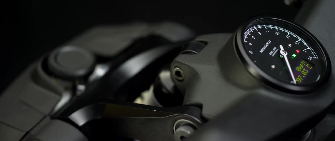 A dark faced motogadget motorcycle speedometer