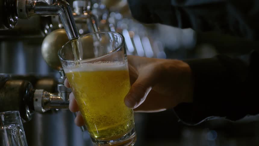 Person dispenses beer from a spout in a bar