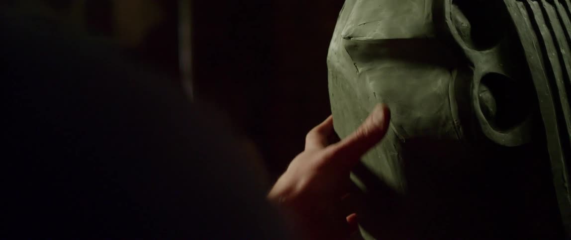 A sculptor smooths a clay seam line with their thumb and fingers