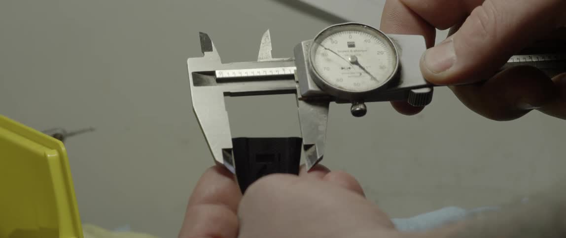 A person uses a dial caliper for measurement