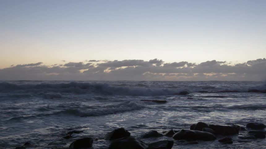 Waves rolling onto a rocky beach at sunrise