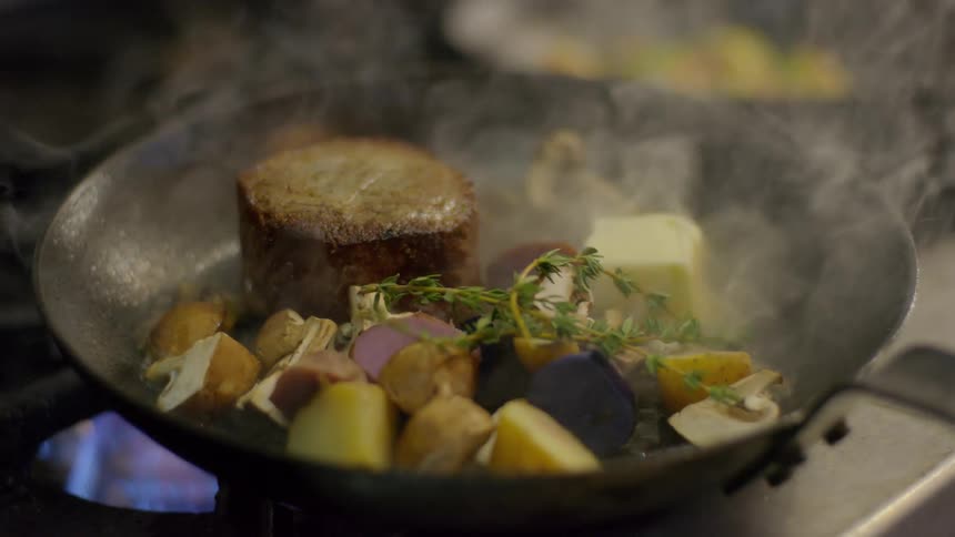 Food cooks over a flame in a frying pan