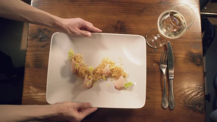 A person is setting a plate of food on a table