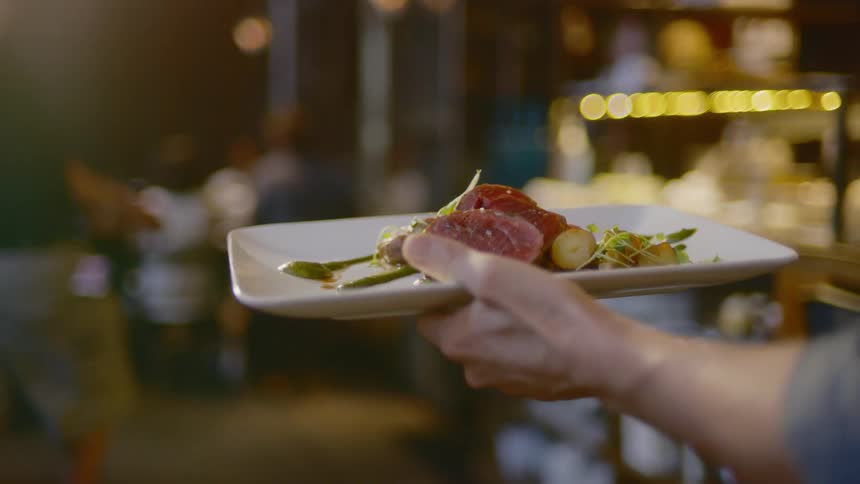 A server carries a plate of food through the dining room
