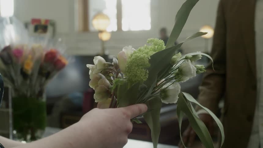 Woman arranges flowers near lamp lit back to back benches
