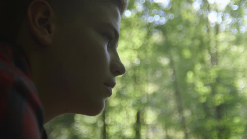 Boy stands and looks a head in the forest