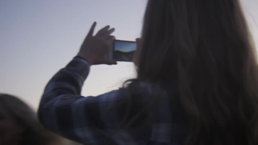A young girl takes photos with her cellphone of another girl