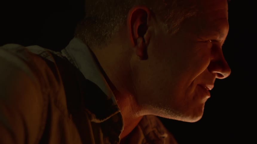 A caucasian man talking near a campfire at night
