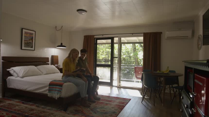 A man and woman sit on a bed togther