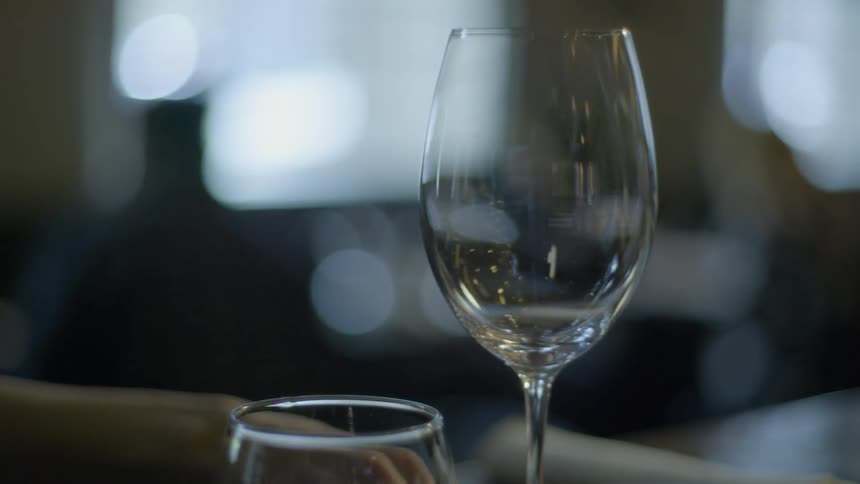 A person pushes an empty wine glass across a table