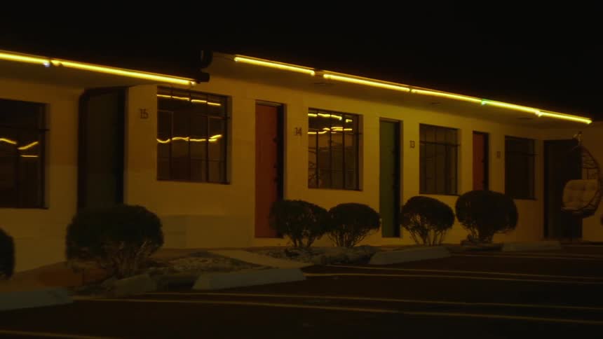 Headlights flash in front of a one story apartment building at night