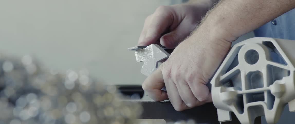 A person files material off a part