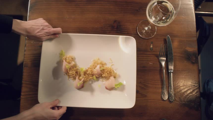 A woman sets a plate of food on a table