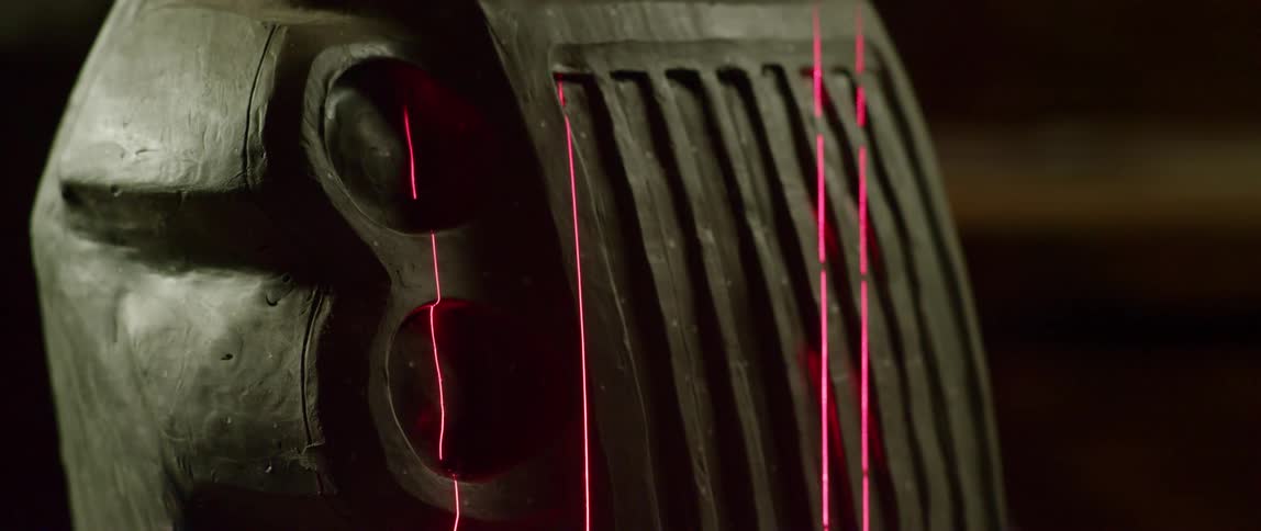 Pink lasers form vertical lines on a large black grate