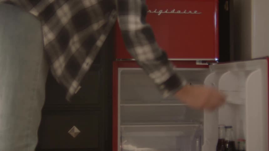 A man grabs a soda from the fridge